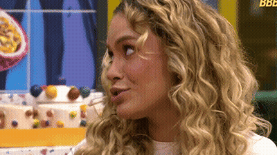 A Woman With Blonde Curly Hair Looks To The Side GIF