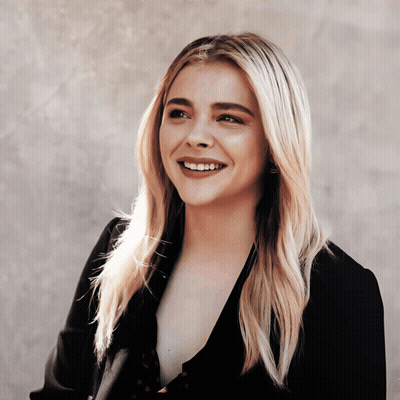 A Woman With Blonde Hair And A Black Jacket Smiles GIF