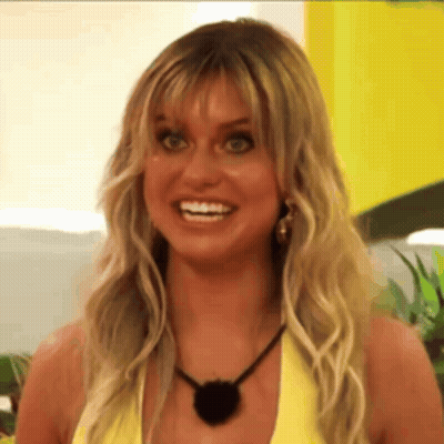 A Woman With Blonde Hair And A Black Necklace Is Smiling GIF