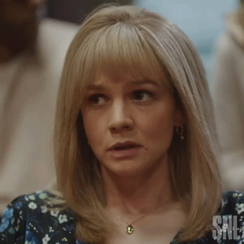 A Woman With Blonde Hair And A Necklace Is Making A Funny Face . GIF