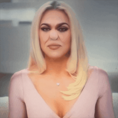 A Woman With Blonde Hair And A Plunging Neckline Is Wearing A Pink Top GIF