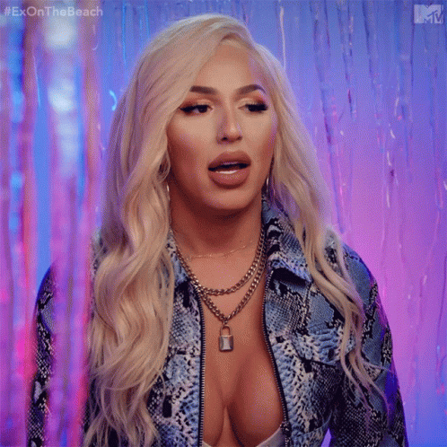 A Woman With Blonde Hair And A Plunging Neckline Is Wearing A Snakeskin Jacket GIF