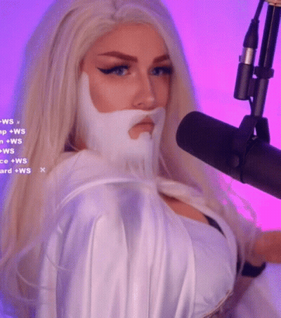 A Woman With Blonde Hair And A White Beard Is Standing In Front Of A Microphone GIF
