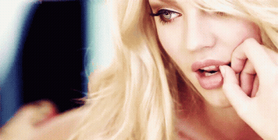 A Woman With Blonde Hair And Blue Eyes Is Biting Her Nails GIF