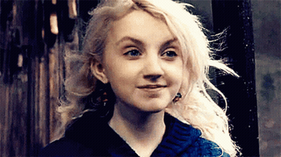 A Woman With Blonde Hair And Blue Eyes Is Smiling And Wearing A Blue Sweater . GIF