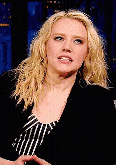 A Woman With Blonde Hair And Blue Eyes Is Wearing A Black Jacket And Striped Shirt GIF