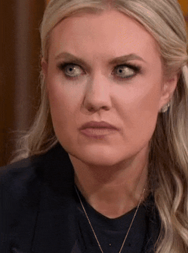 A Woman With Blonde Hair And Blue Eyes Is Wearing A Necklace GIF