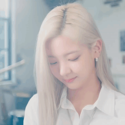 A Woman With Blonde Hair And Blue Eyes Is Wearing A White Shirt . GIF