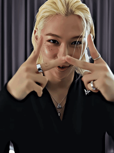 A Woman With Blonde Hair And Freckles Making A Peace Sign With Her Hands GIF