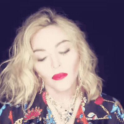 A Woman With Blonde Hair And Red Lips Is Wearing A Floral Shirt GIF