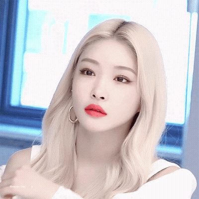 A Woman With Blonde Hair And Red Lips Is Wearing Hoop Earrings And A White Top GIF