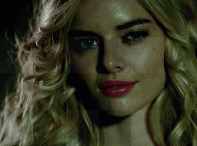 A Woman With Blonde Hair And Red Lips Looks At The Camera GIF