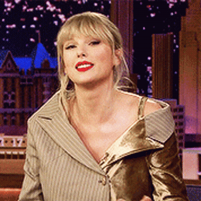 A Woman With Blonde Hair And Red Lipstick Is Wearing A Tan Striped Jacket GIF