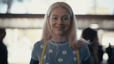 A Woman With Blonde Hair And White Eye Shadow Smiles For The Camera GIF