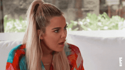 A Woman With Blonde Hair In A Ponytail Is Sitting On A Couch With The Letter E On The Bottom Right GIF