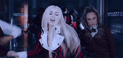 A Woman With Blonde Hair Is Dancing In A Crowded Room While Two Other Women Look On . GIF