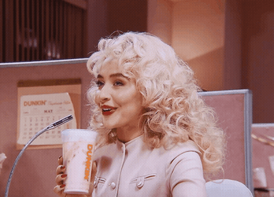 A Woman With Blonde Hair Is Drinking From A Dunkin Donuts Cup GIF