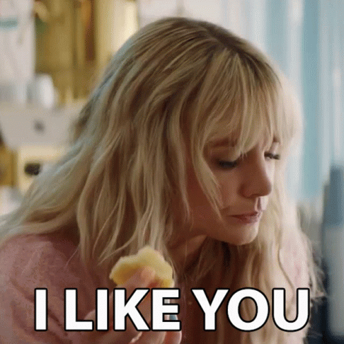 A Woman With Blonde Hair Is Eating A Piece Of Food And Says I Like You GIF