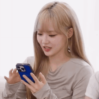 A Woman With Blonde Hair Is Holding A Cell Phone In Her Hand . GIF