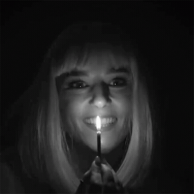 A Woman With Blonde Hair Is Holding A Lit Match In Her Mouth .. GIF