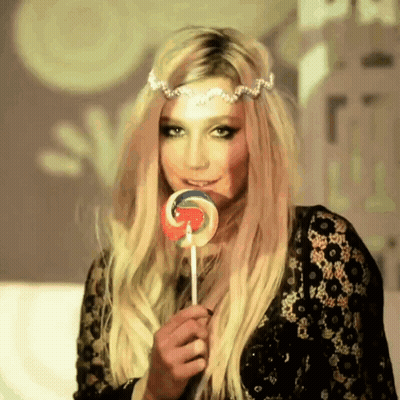 A Woman With Blonde Hair Is Holding A Lollipop In Her Hand GIF