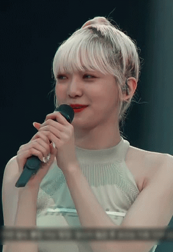 A Woman With Blonde Hair Is Holding A Microphone In Her Hand GIF