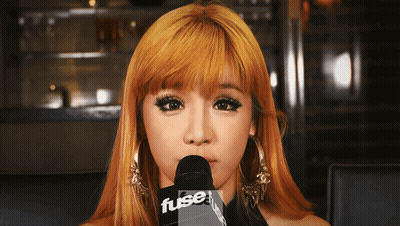 A Woman With Blonde Hair Is Holding A Microphone That Says Fuse GIF