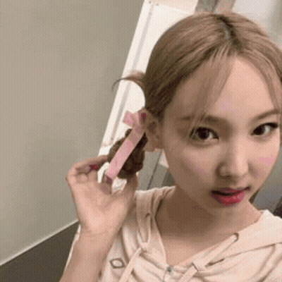 A Woman With Blonde Hair Is Holding A Pink Ribbon In Her Hair . GIF