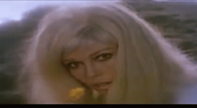 A Woman With Blonde Hair Is Holding A Yellow Flower In Her Hand . GIF