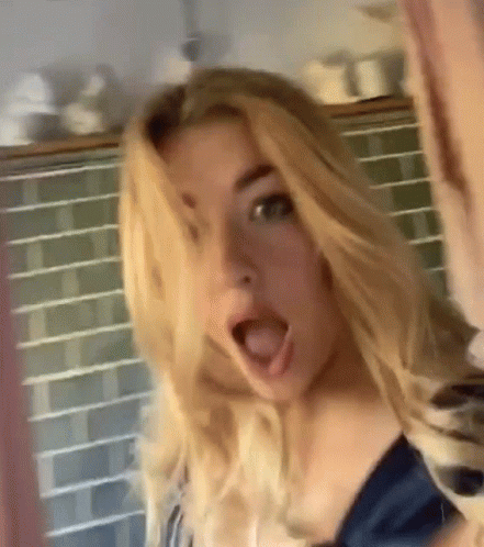 A Woman With Blonde Hair Is Making A Surprised Face With Her Mouth Open GIF