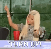 A Woman With Blonde Hair Is Sitting At A Table With A Red Cup In Her Hand . GIF