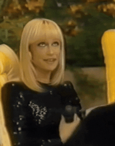 A Woman With Blonde Hair Is Sitting In A Chair GIF