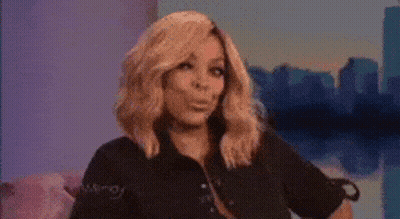 A Woman With Blonde Hair Is Sitting On A Couch In Front Of A City Skyline . GIF