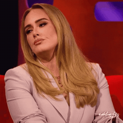 A Woman With Blonde Hair Is Sitting On A Red Couch With The Words Edelagifs Written On The Bottom GIF