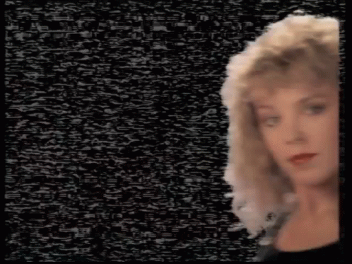 A Woman With Blonde Hair Is Standing In Front Of A Black Background With A Lot Of Static . GIF