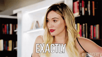A Woman With Blonde Hair Is Standing In Front Of A Bookshelf And Says Exactly . GIF