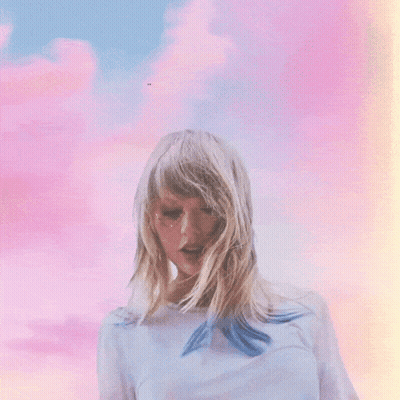 A Woman With Blonde Hair Is Standing In Front Of A Cloudy Sky GIF