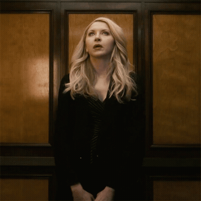 A Woman With Blonde Hair Is Standing In Front Of A Wall GIF