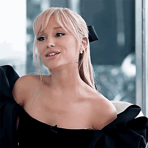 A Woman With Blonde Hair Is Wearing A Black Dress GIF