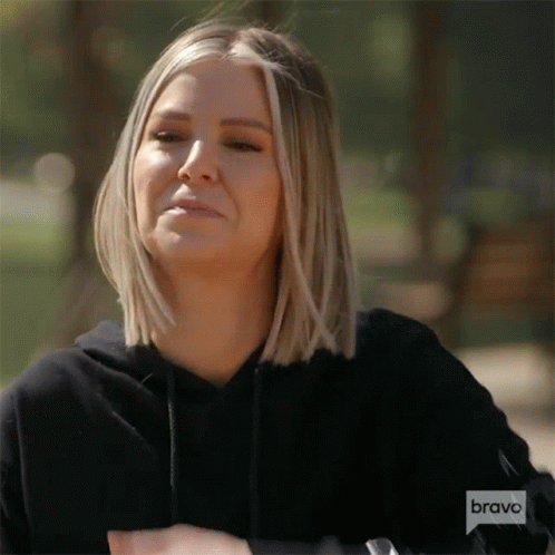A Woman With Blonde Hair Is Wearing A Black Hoodie And A Watch . GIF