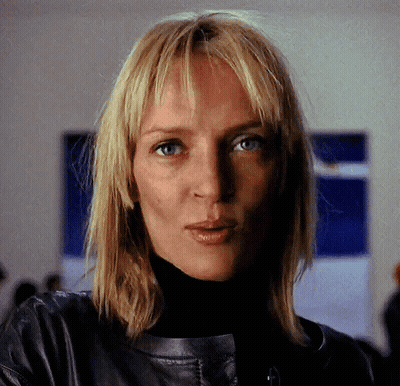 A Woman With Blonde Hair Is Wearing A Black Turtleneck And A Leather Jacket GIF