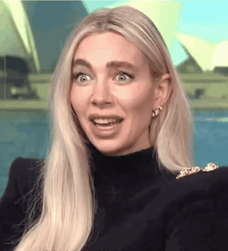 A Woman With Blonde Hair Is Wearing A Black Turtleneck And Gold Earrings GIF