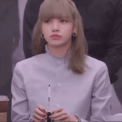 A Woman With Blonde Hair Is Wearing A Blue Shirt And Holding A Pen In Her Hands . GIF