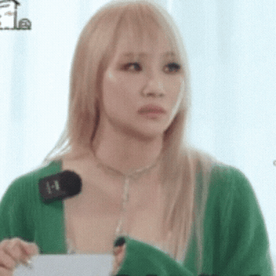 A Woman With Blonde Hair Is Wearing A Green Sweater And Holding A Microphone In Her Hand . GIF