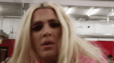A Woman With Blonde Hair Is Wearing A Pink Shirt And Making A Funny Face GIF