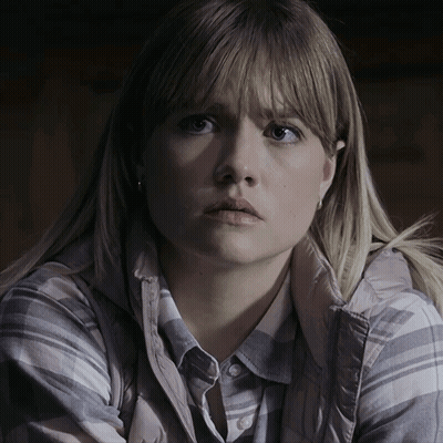 A Woman With Blonde Hair Is Wearing A Plaid Shirt And A Grey Vest GIF