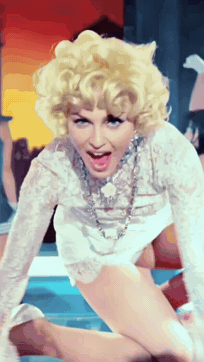 A Woman With Blonde Hair Is Wearing A White Dress And A Necklace GIF