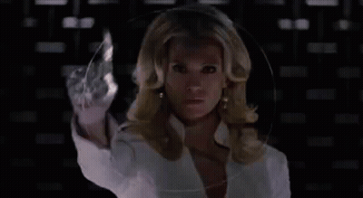 A Woman With Blonde Hair Is Wearing A White Jacket And Earrings . GIF