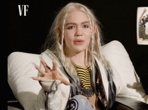 A Woman With Blonde Hair Is Wearing A White Jacket GIF