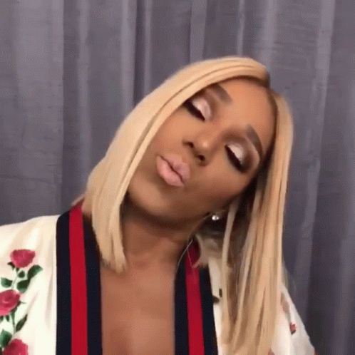 A Woman With Blonde Hair Is Wearing A White Robe With Roses On It . GIF